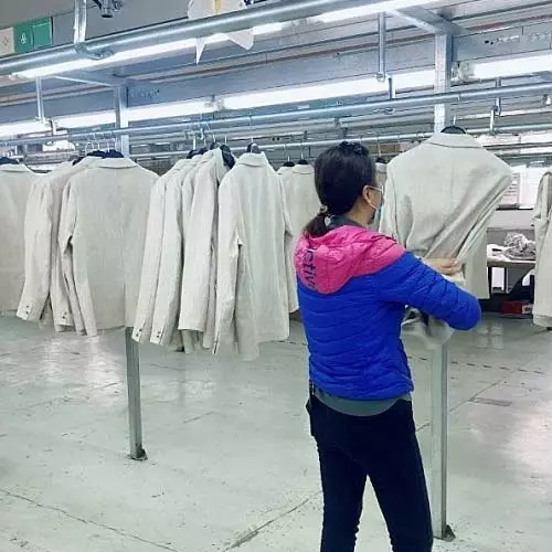 Woman at a clothing factory is inspecting a jacket.